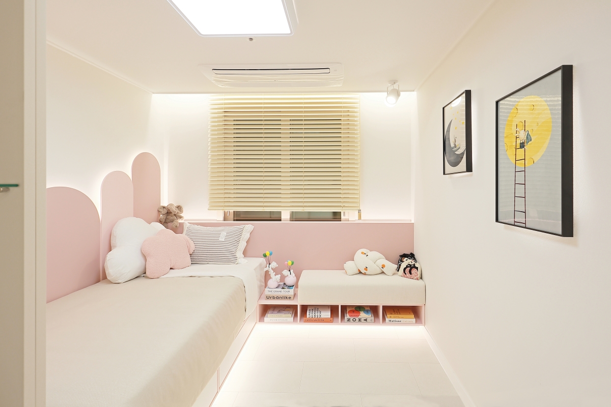 60B 타입 주택홍보관 자녀방 — 핑크 아치형 헤드보드와 침대, 인형이 놓인 수납 벤치, 우드 블라인드 창과 일러스트 액자가 걸린 방